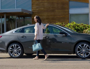 A waman exiting a grey 2023 Chevy Malibu parked on a street near Parsons, Kansas.